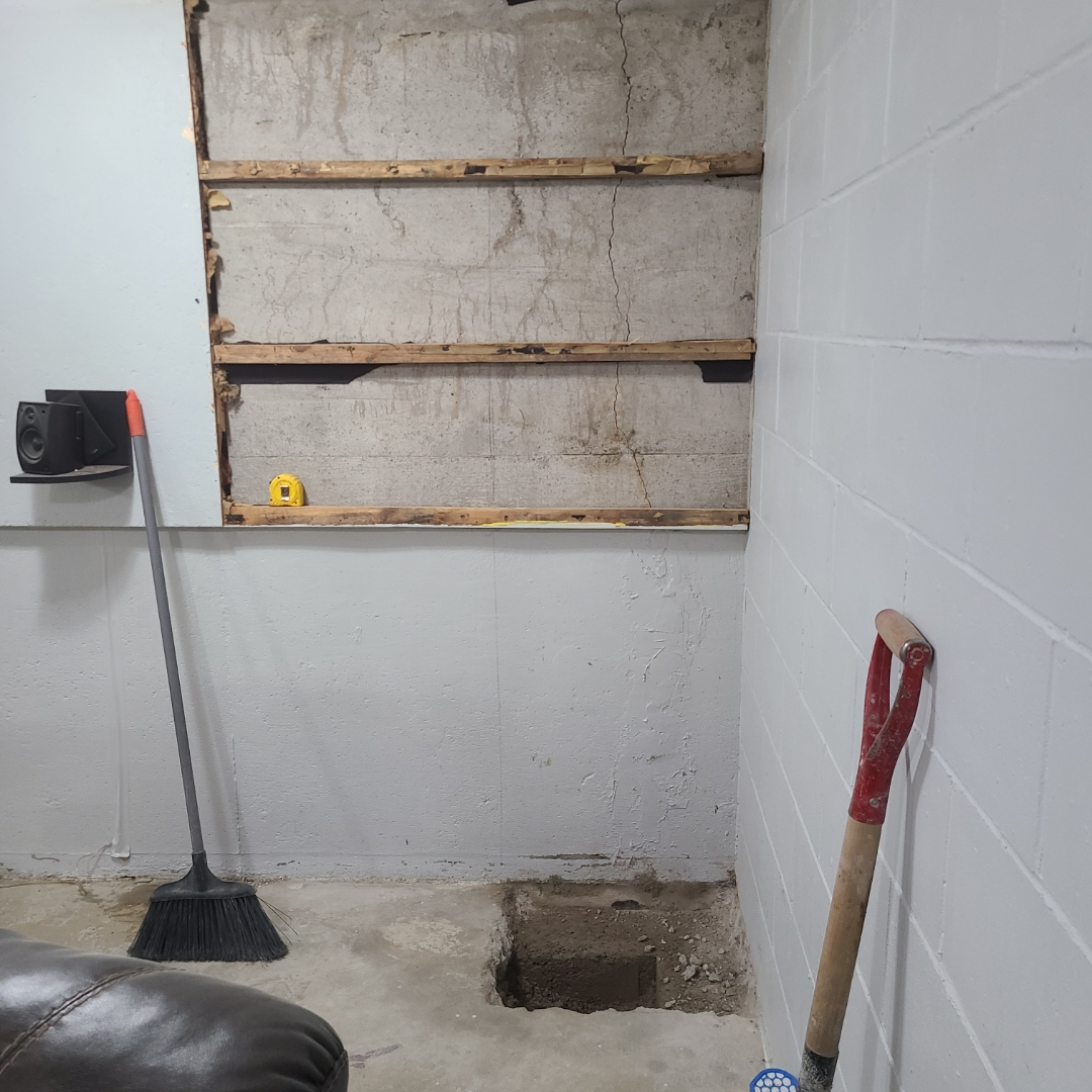 Cracked, exposed basement foundation wall with the floor opened up before repair