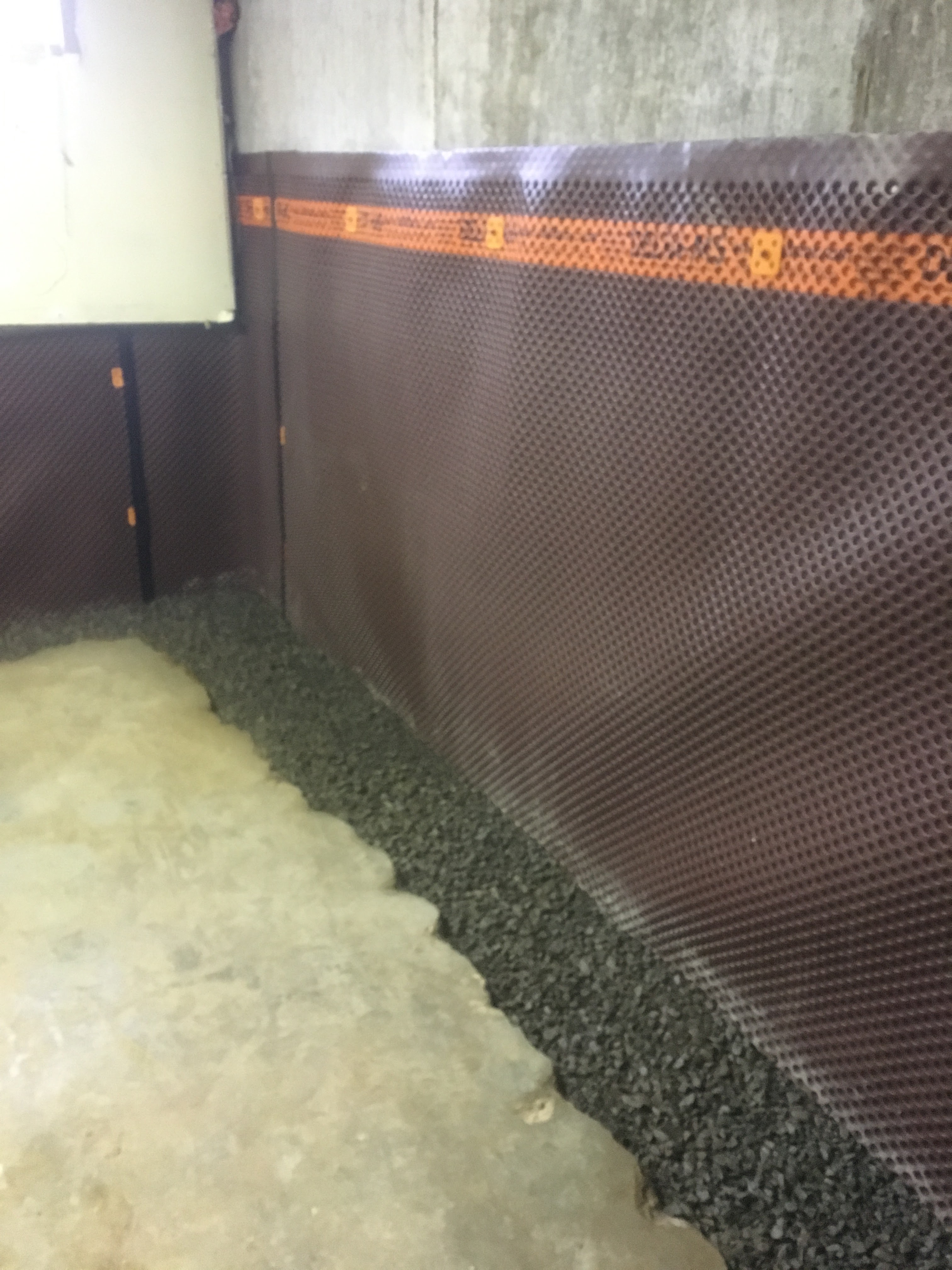 Delta-MS dimpled drainage membrane installed along a basement foundation wall with gravel drainage at the base