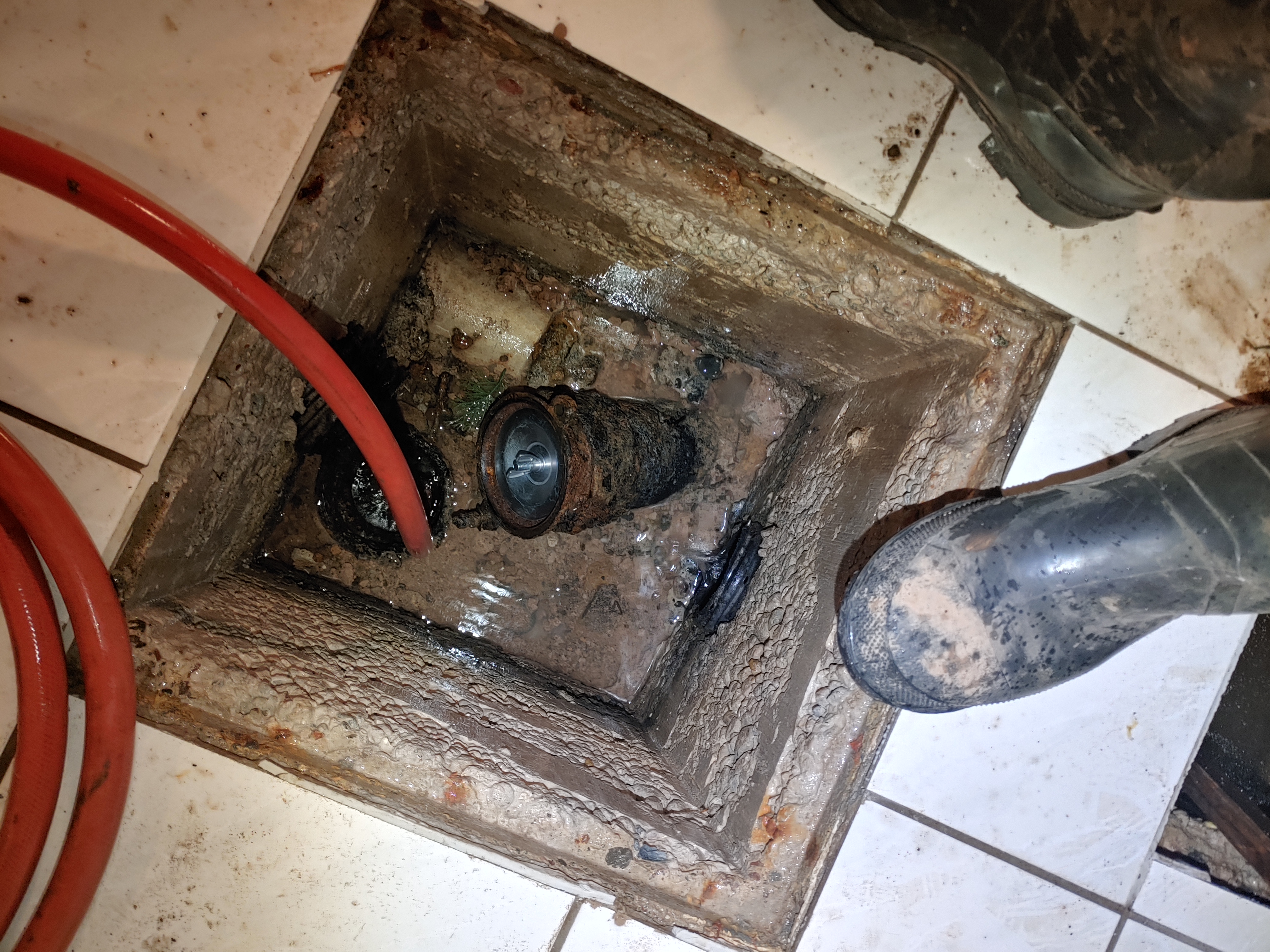 Rooley Group technician flushing a weeping tile access point with a high-pressure hose